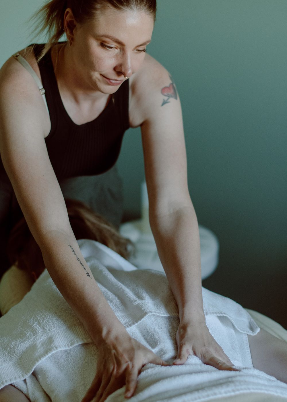 Massage therapist in action, using green-toned branding colors, creating a calming atmosphere while providing a massage.