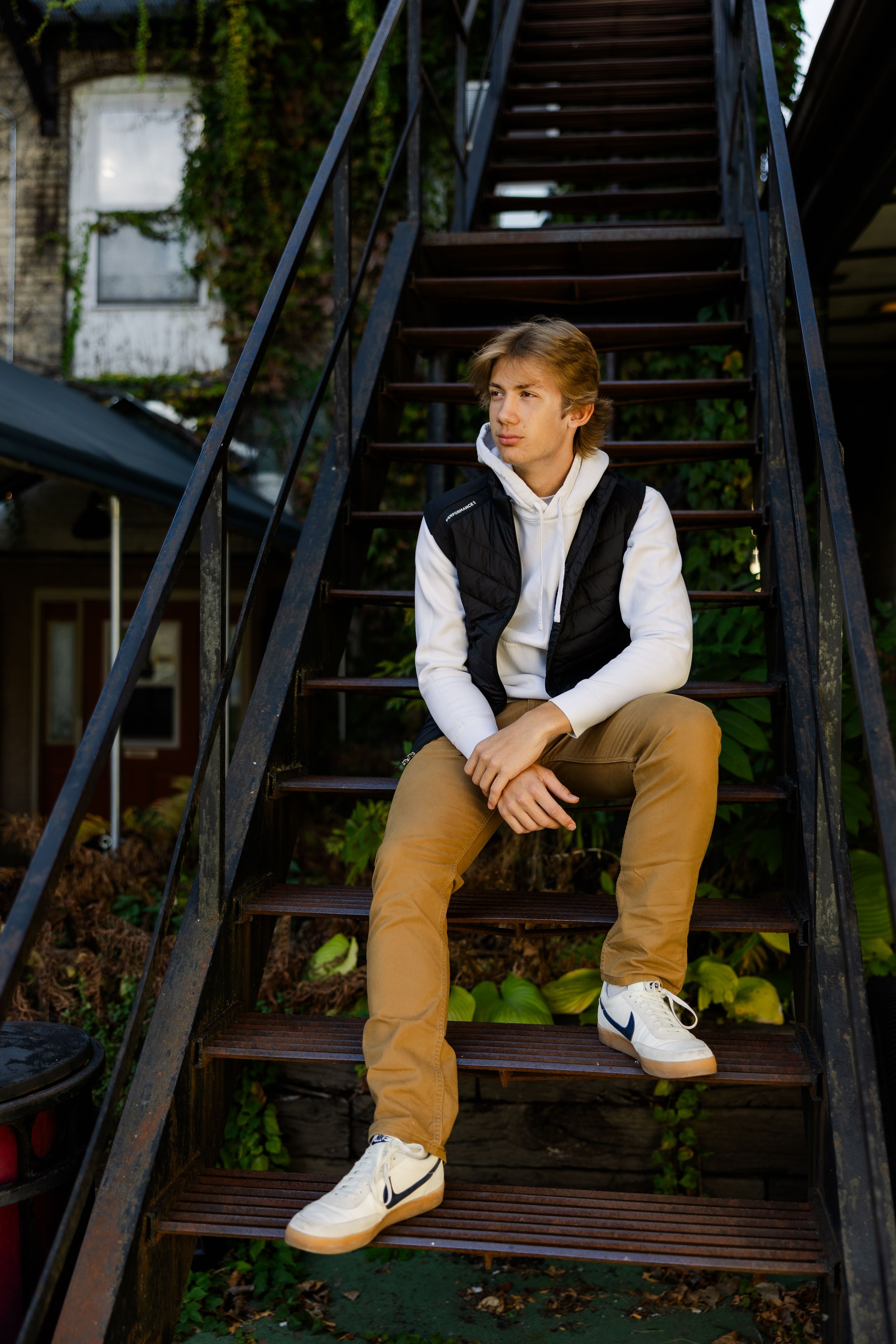 High school senior sitting on black metal steps in an urban setting