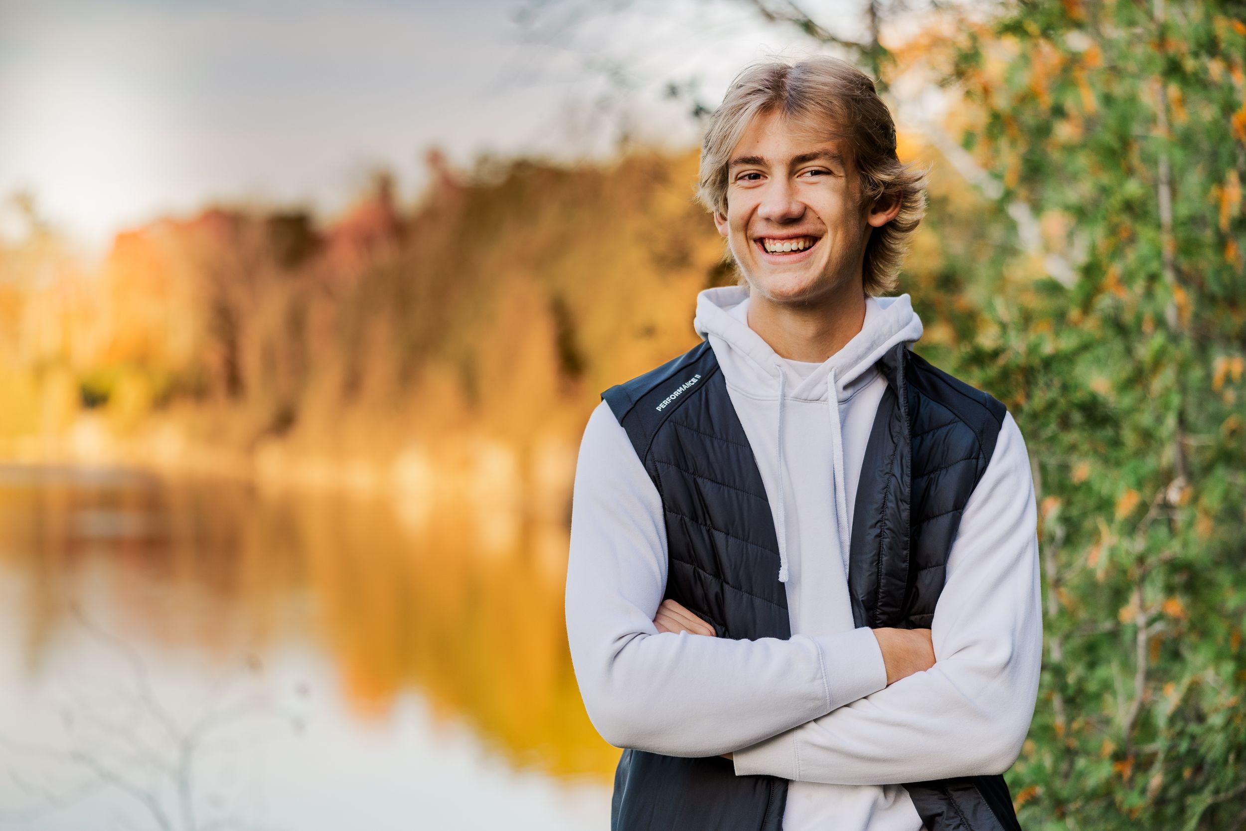High school senior standing on the edge of a quarry surrounded by vibrant fall trees.
