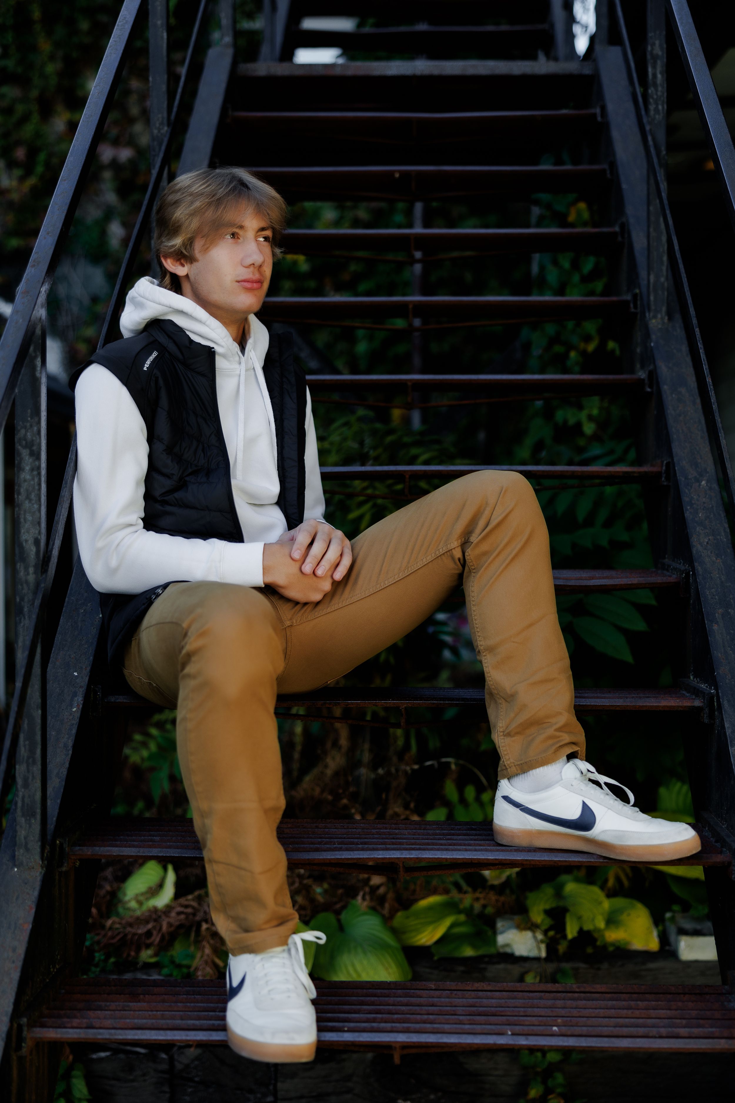 High school senior sitting on black metal steps in an urban setting