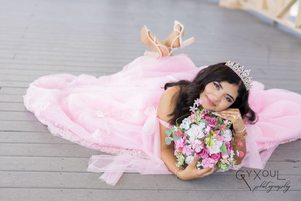 An artistic overhead shot of a pink ball gown and floral bouquet on wooden decking.