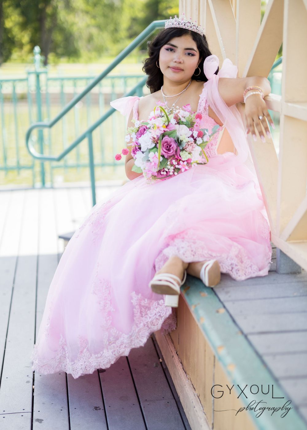 A casual posed shot on outdoor steps showing a flowing pink ball gown and bouquet.