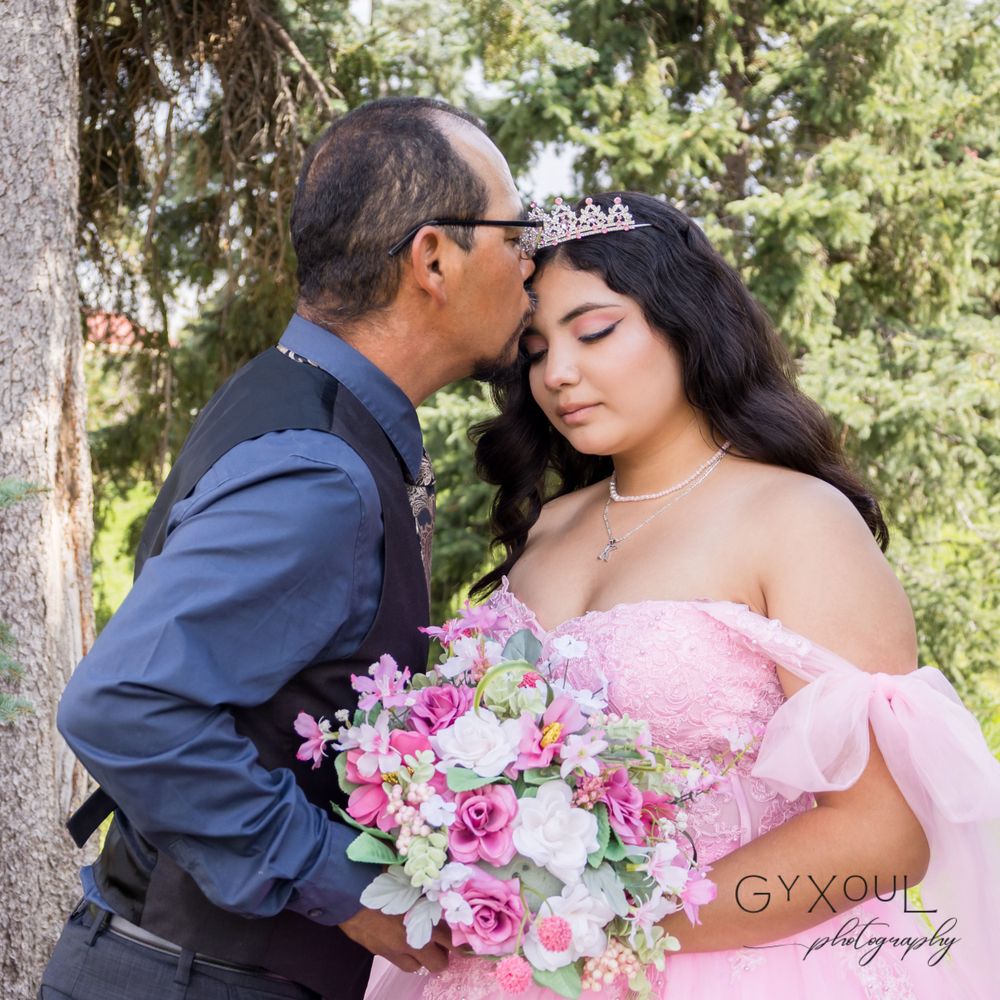A tender moment captured with a pink ball gown and floral bouquet in an outdoor setting.