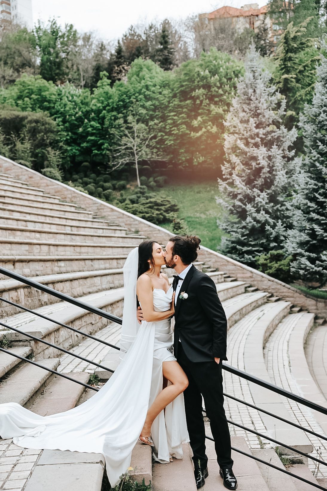 Dramatic wedding portrait on stone amphitheater steps with flowing veil.