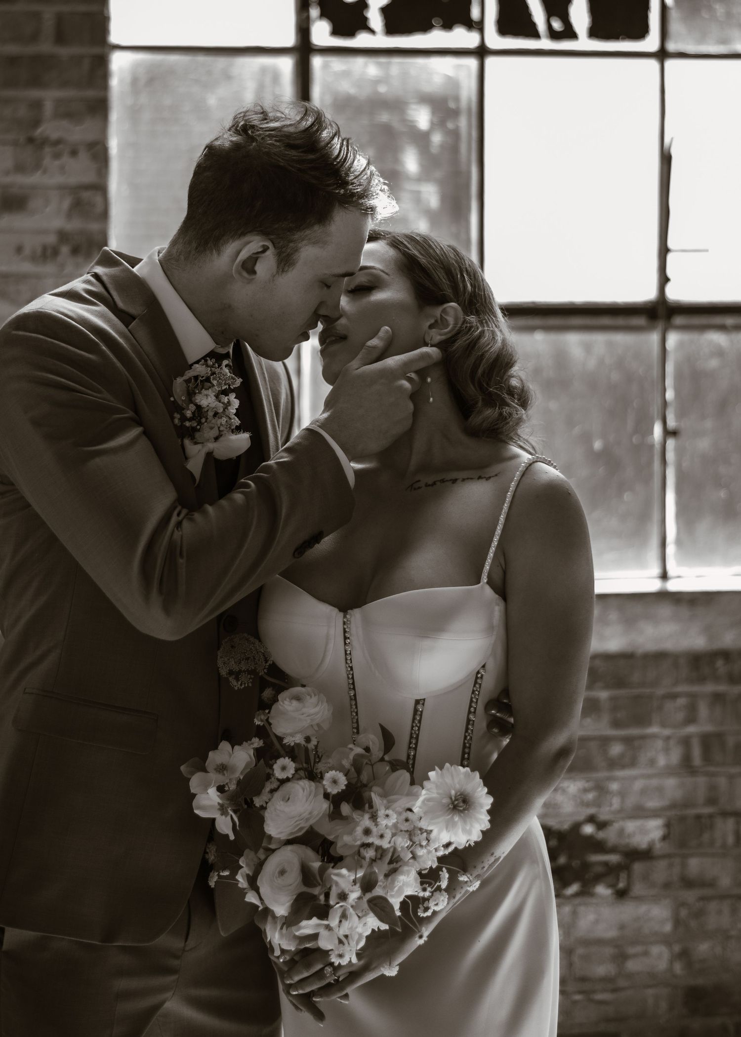Wedding couple sharing romantic moments in front of an industrial brick wall backdrop.