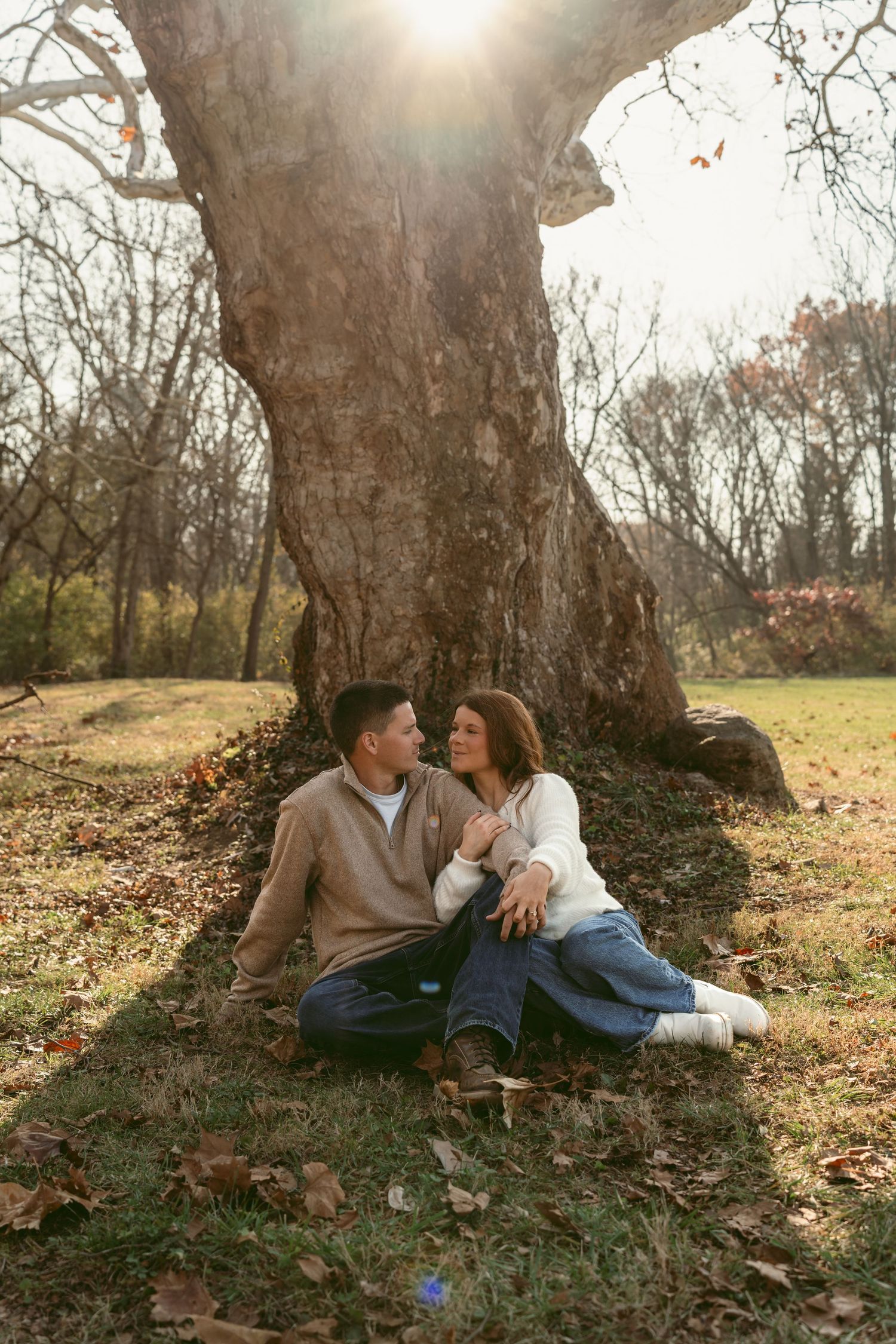 An engagement photo session at Hidden Valley Orchard in Lebanon Ohio with a couple posing near a tree looking at each other smiling.