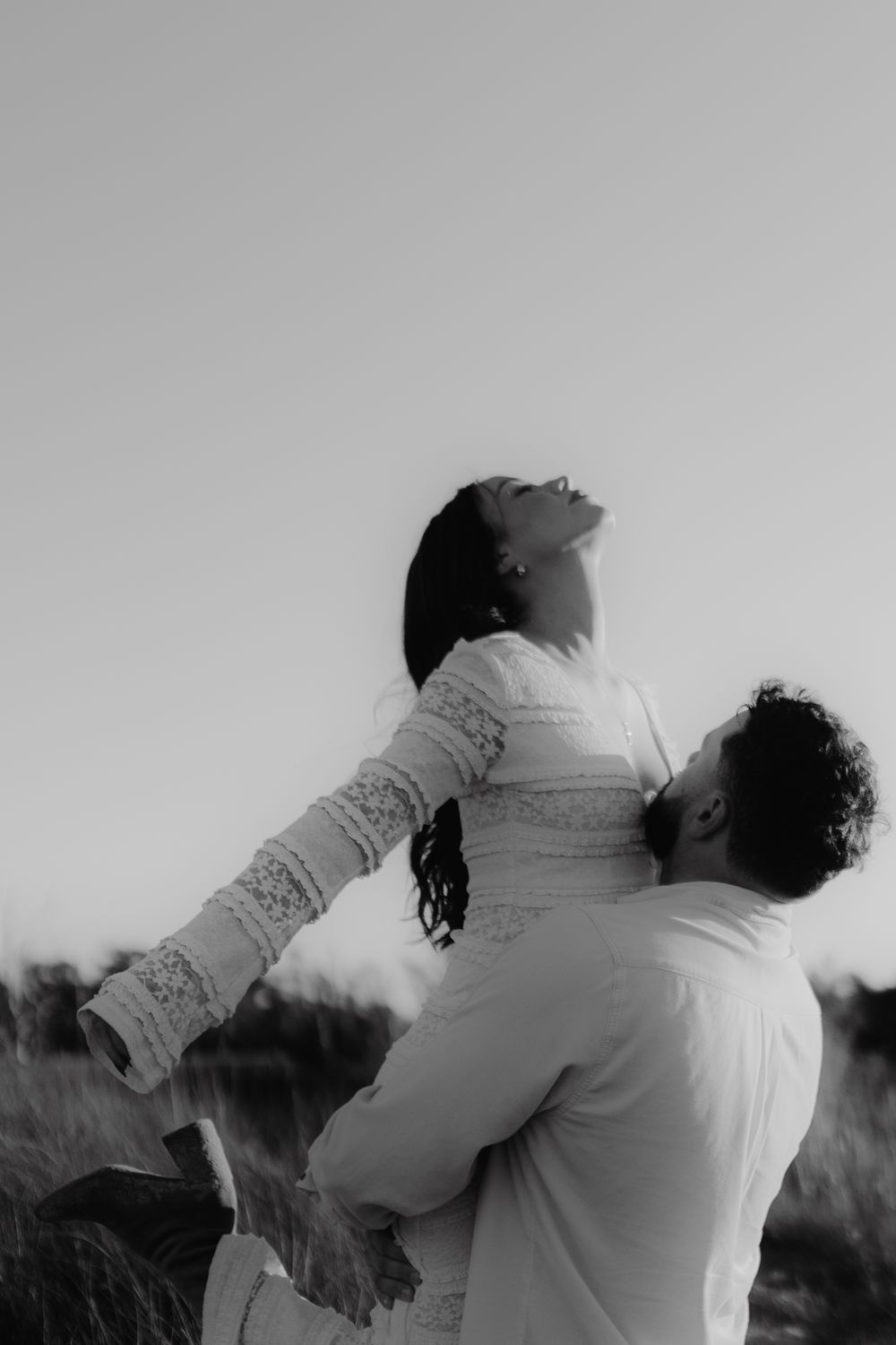 A dramatic black and white shot of a couple in an intimate embrace outdoors.