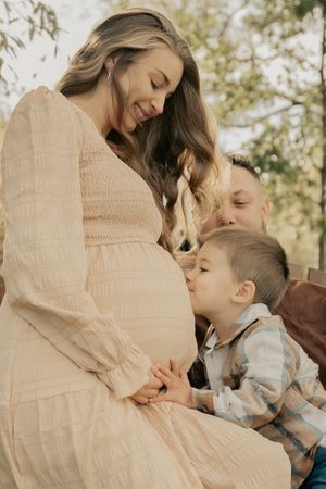 A touching maternity moment on a sunny day outdoors with a growing family.
