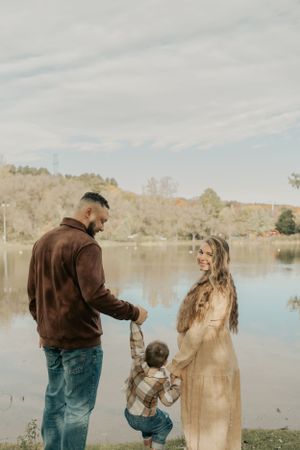A tender family moment captured by a serene lake during autumn.