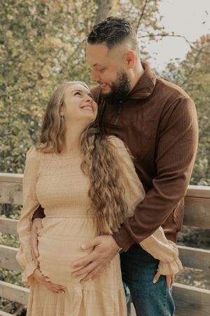An intimate maternity portrait against a backdrop of autumn trees.