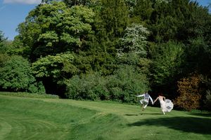 Scenic wedding venue with lush green trees and manicured lawn.