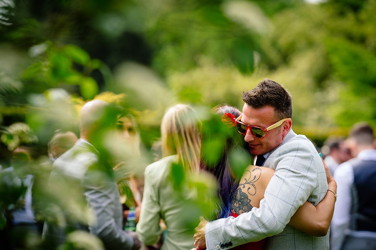 Wedding guests celebrate joyfully in an outdoor garden setting with colorful decorations.