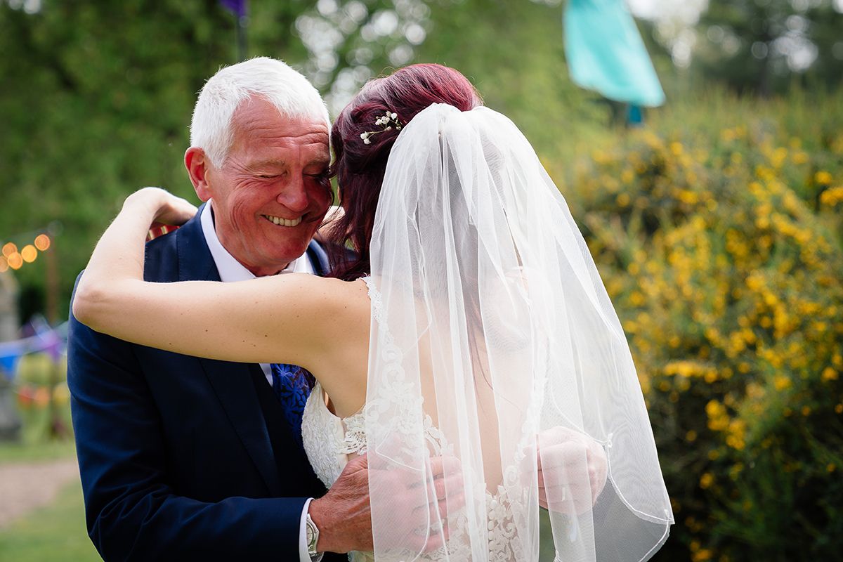 Couple shares an intimate moment during their outdoor wedding ceremony surrounded by greenery.
