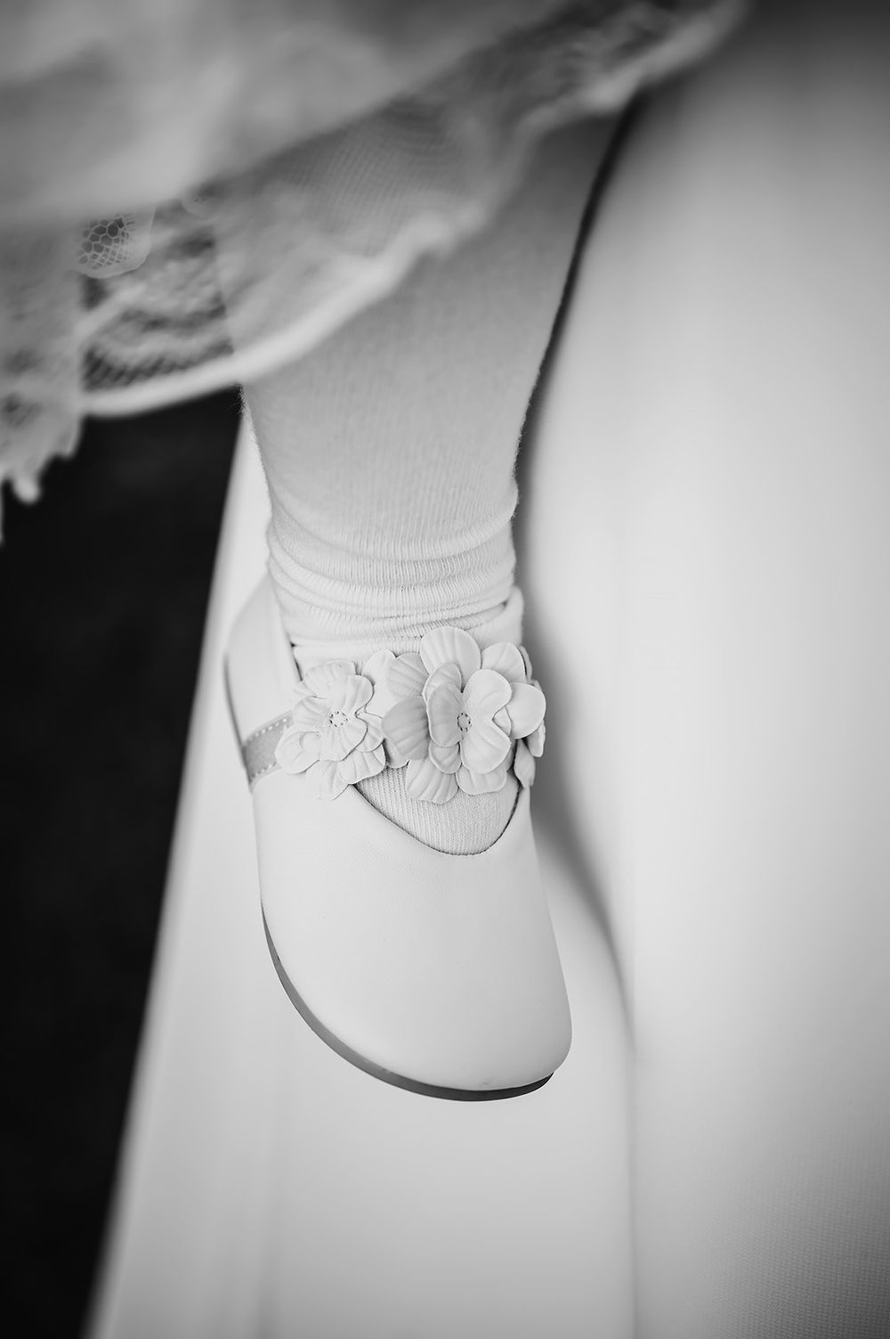 Detaljfoto av en liten vacker sandal som bärs av en brudnäbb på ett bröllop. En vit bröllopssko med blommor för barn.