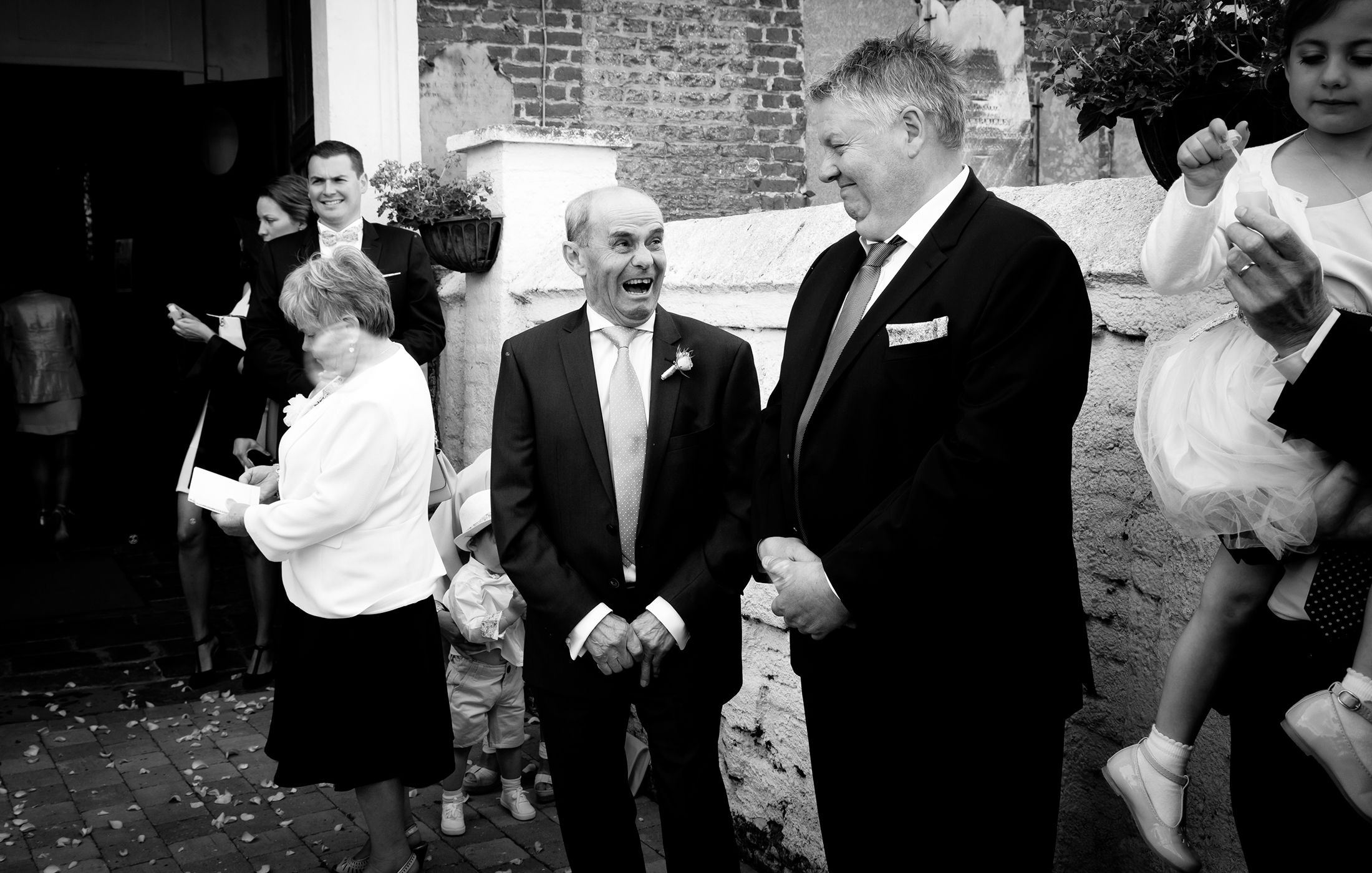 A black and white photo collage showing candid moments from a wedding celebration.