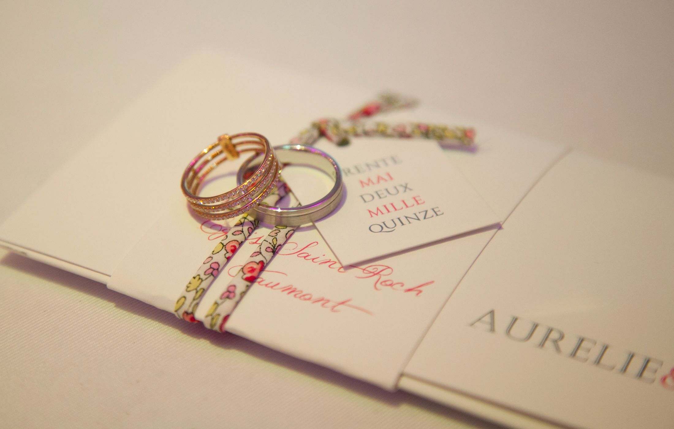 Wedding rings and invitation cards arranged in a sequence showing elegant wedding stationery details.