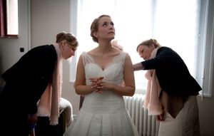 Wedding party preparations with elegant white dresses and formal attire in a sunlit room.