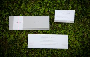 A series of white paper notes arranged in a row against a lush green hedge background.
