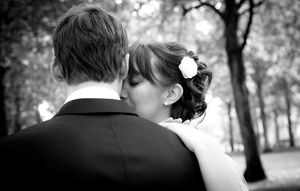 A romantic black and white wedding moment captured from behind in a wooded setting.
