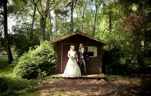 A wooded outdoor wedding venue with rustic wooden cabins and natural forest scenery in the background.
