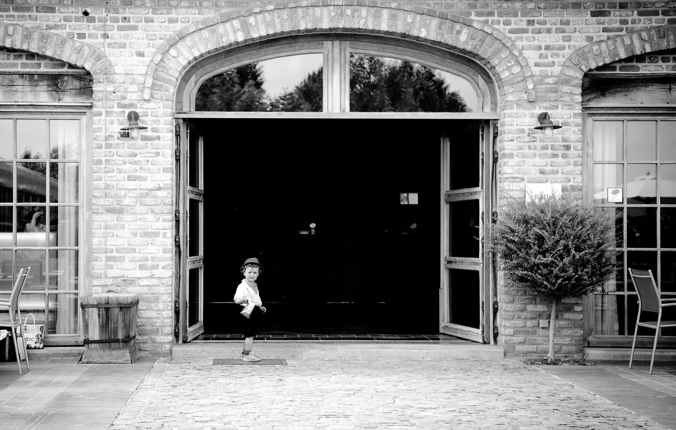 A series of arched doorways and entrances along a brick building facade with stone accents and architectural details.