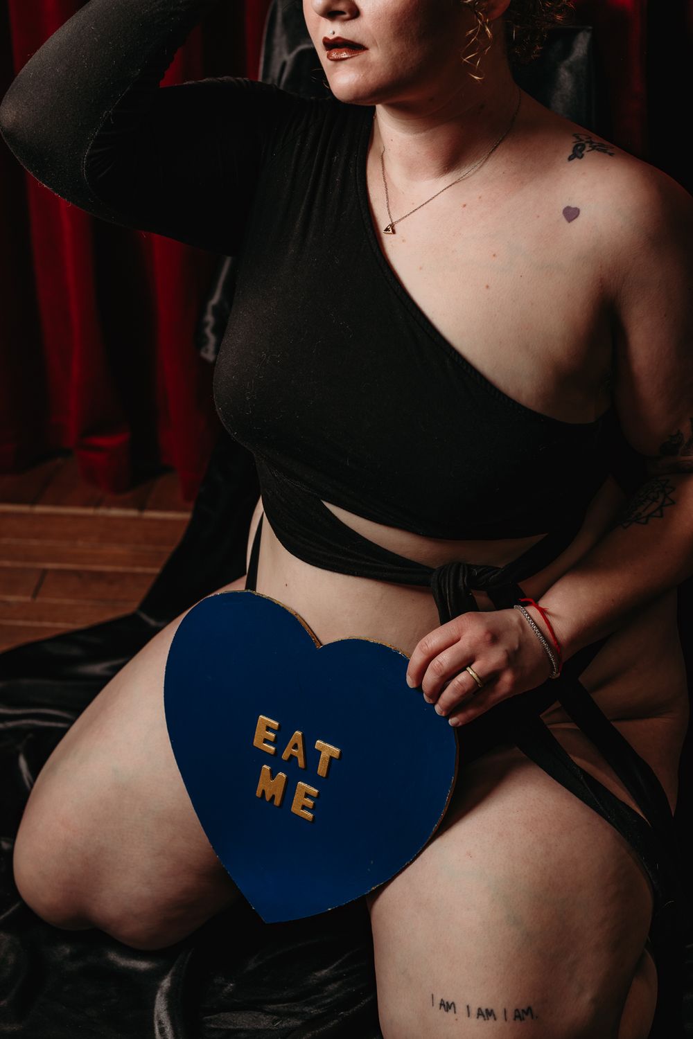 A series of cropped photos showing someone wearing black clothing and blue underwear with text embroidered on it.