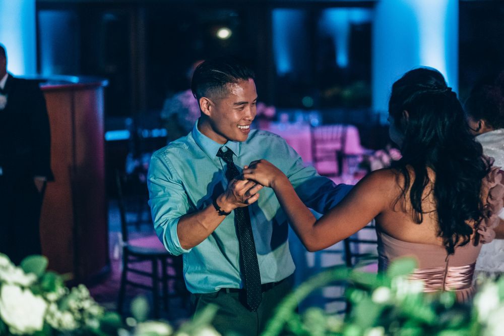 Guests enjoying food and drinks at an elegant indoor reception with blue lighting.