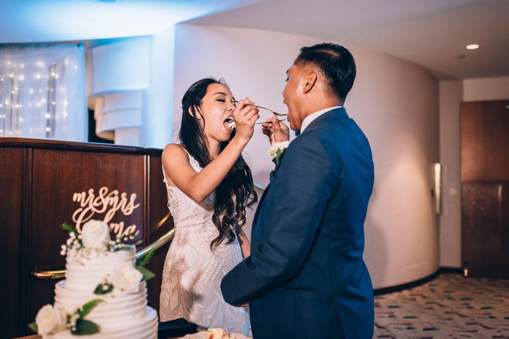 Romantic cake cutting ceremony at wedding reception with soft blue lighting.