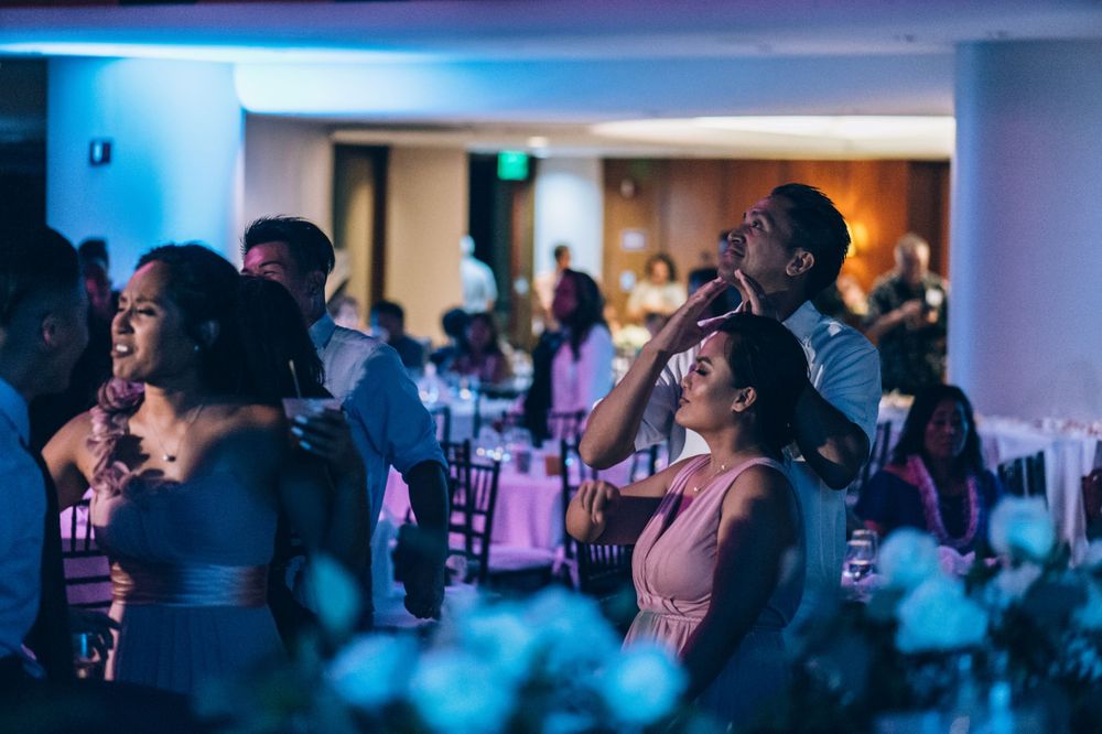 Large reception hall with blue ambient lighting and guests seated at round tables.