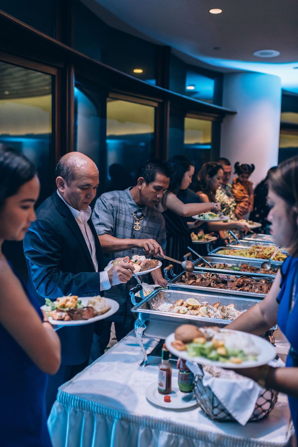 Wedding guests serving themselves at an elegant buffet line with various food options.