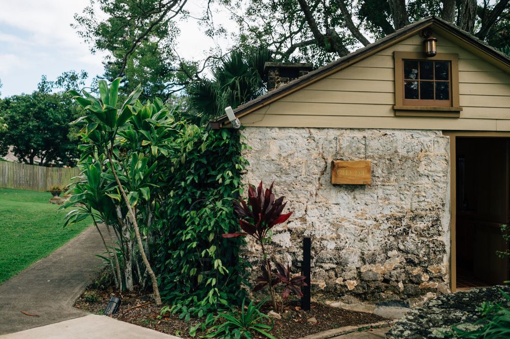 Historic stone building with cream walls and wooden details in a garden setting.