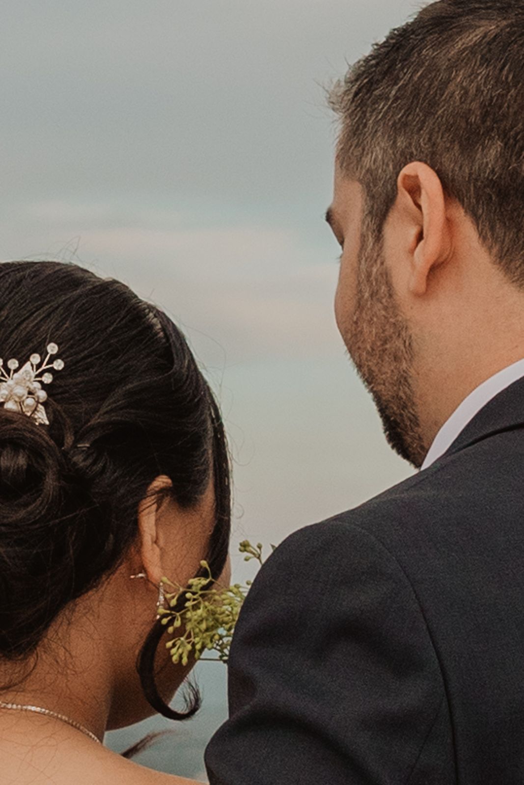 Bride and groom seen from behind sharing intimate moment outdoors on their wedding day.