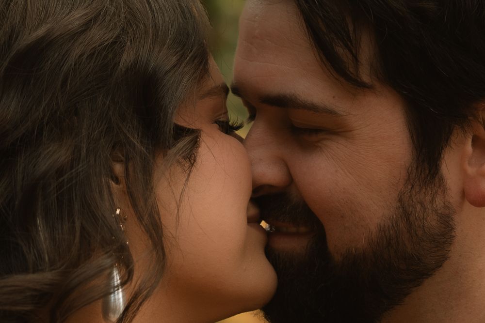 A romantic couple embraces intimately in soft lighting against a dark background.