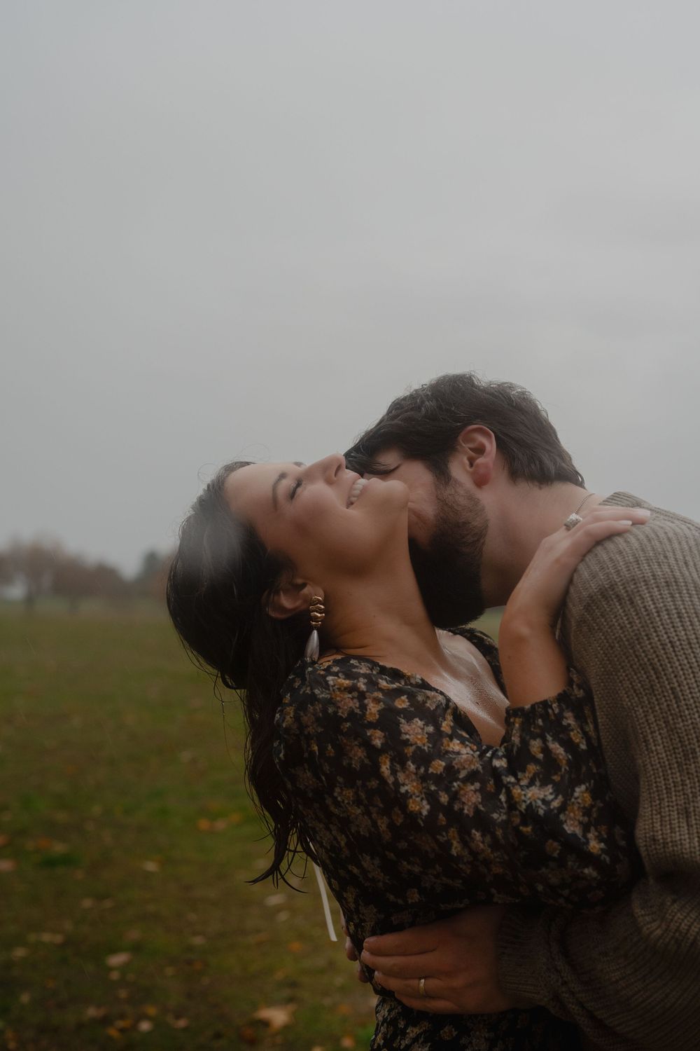 Intimate embrace captured in moody lighting against an overcast autumn sky.