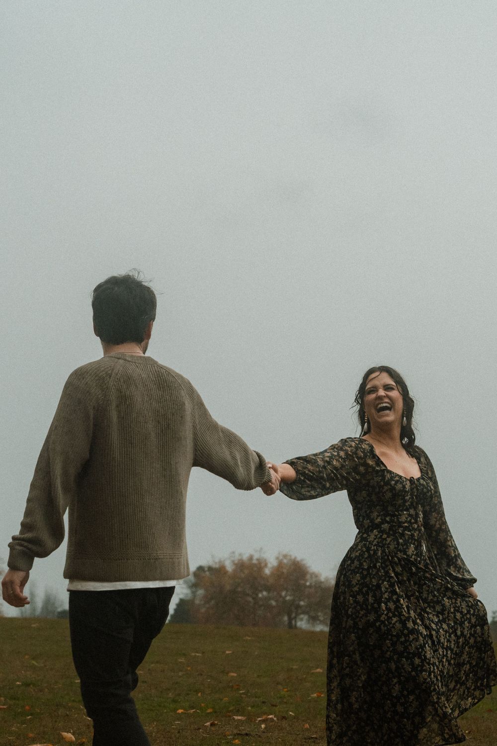 Couple dancing together on misty hillside in casual autumn attire.