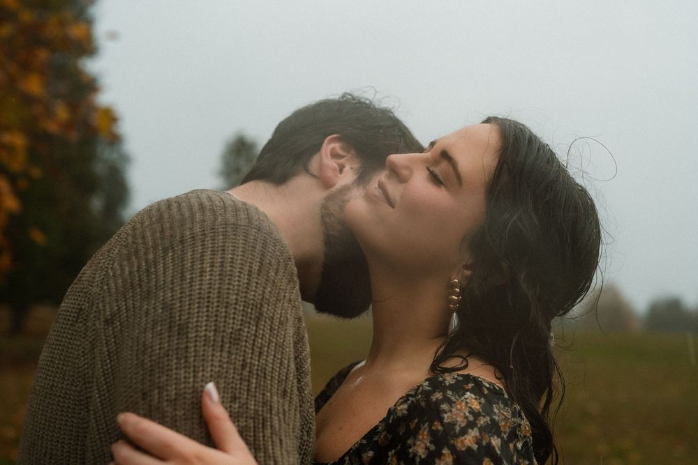Intimate moment captured in foggy autumn field with muted colors.
