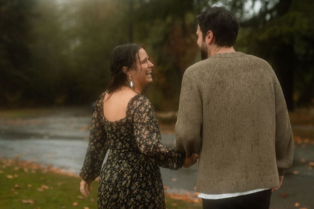 A couple shares a playful dance moment in a park during autumn.