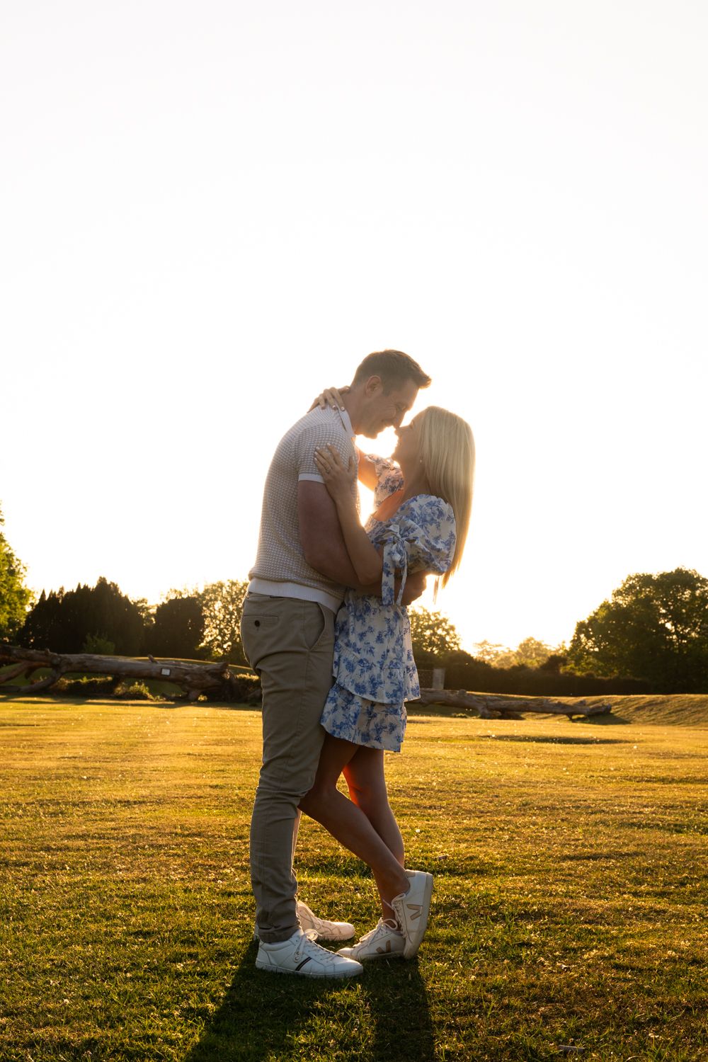A couple embraces in a golden field at sunset creating a romantic silhouette against the glowing sky.