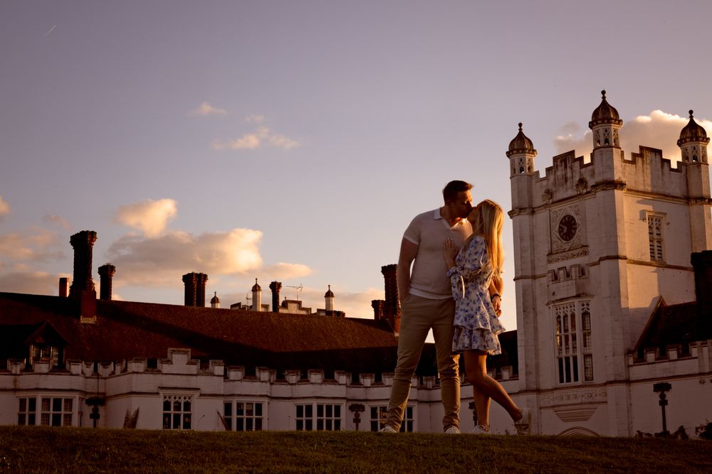Historic mansion with ornate architecture silhouetted against a sunset sky with multiple towers and spires.