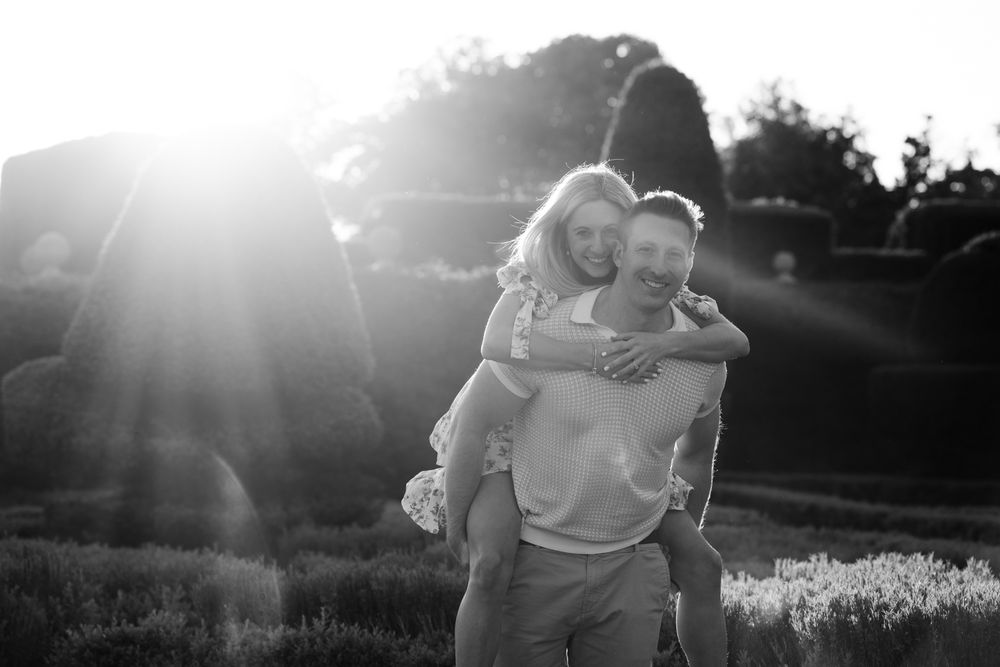 A couple embraces in a romantic outdoor setting during golden hour sunlight.
