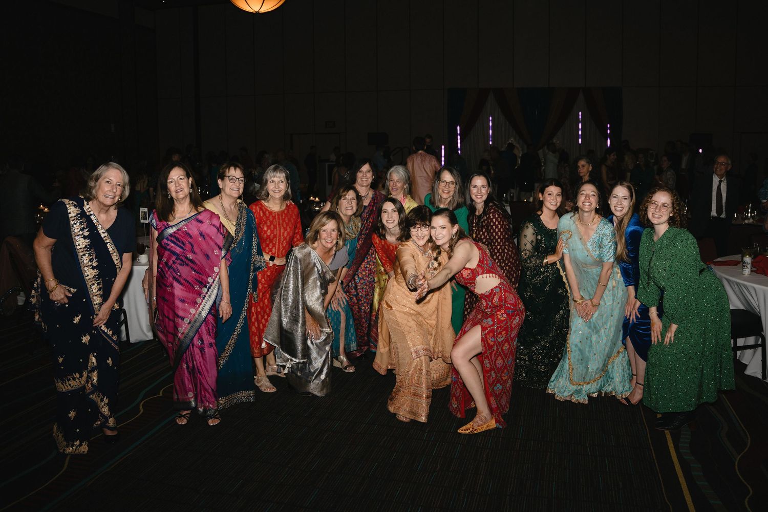 Large group of women in colorful saris and traditional attire posing at Indian wedding reception.at Sandia Resort and Casino