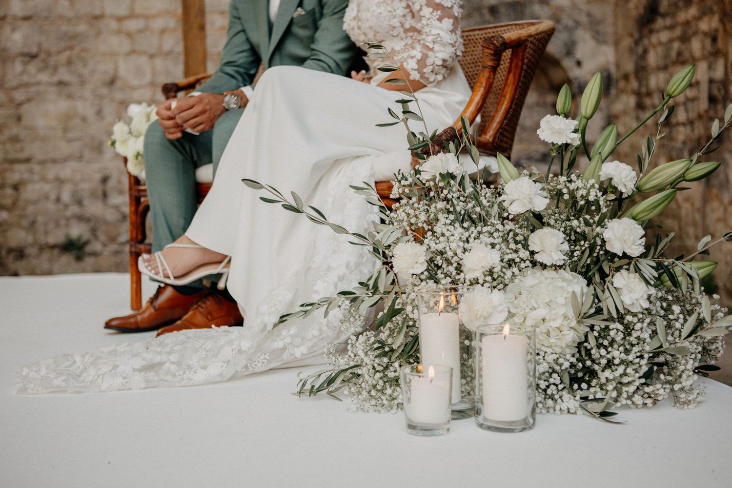 Close-up of wedding ceremony decor featuring white roses, baby's breath, and candles at the altar base.