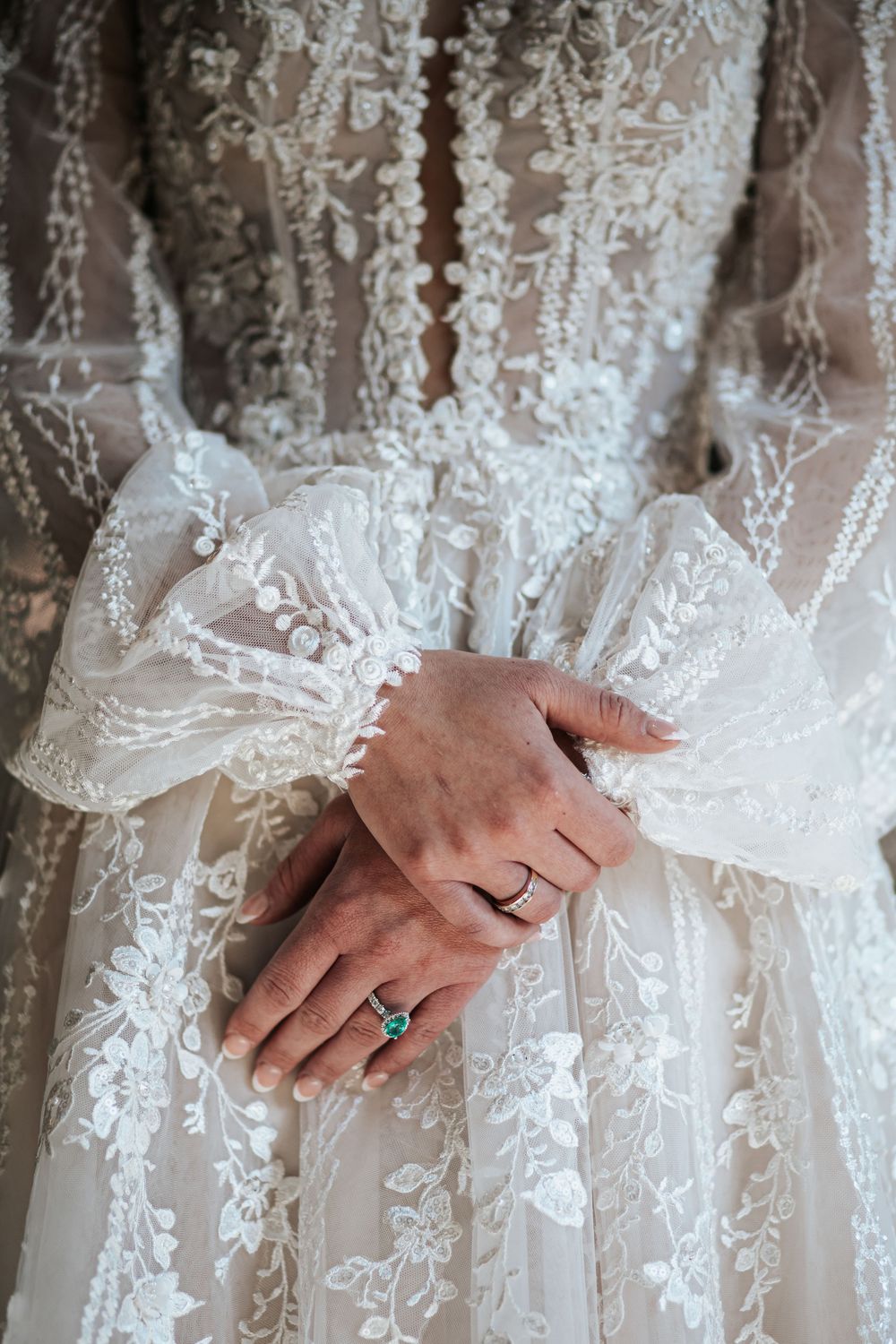 Close-up detail shots of hands against delicate white lace wedding dress fabric showing intricate floral patterns.