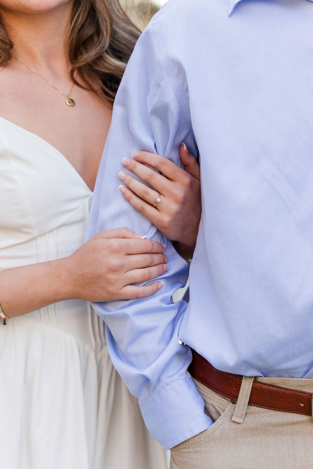 Close-up detail shots of a couple embracing in formal attire showing blue shirt and white dress.