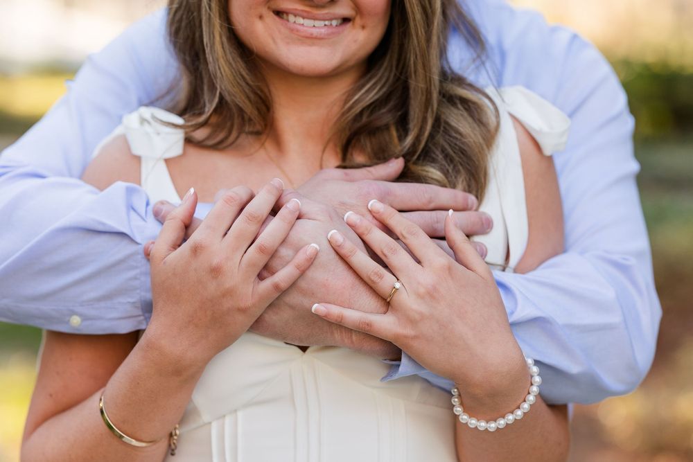 Close up of hands holding each other against a light outdoor background with soft bokeh effect.