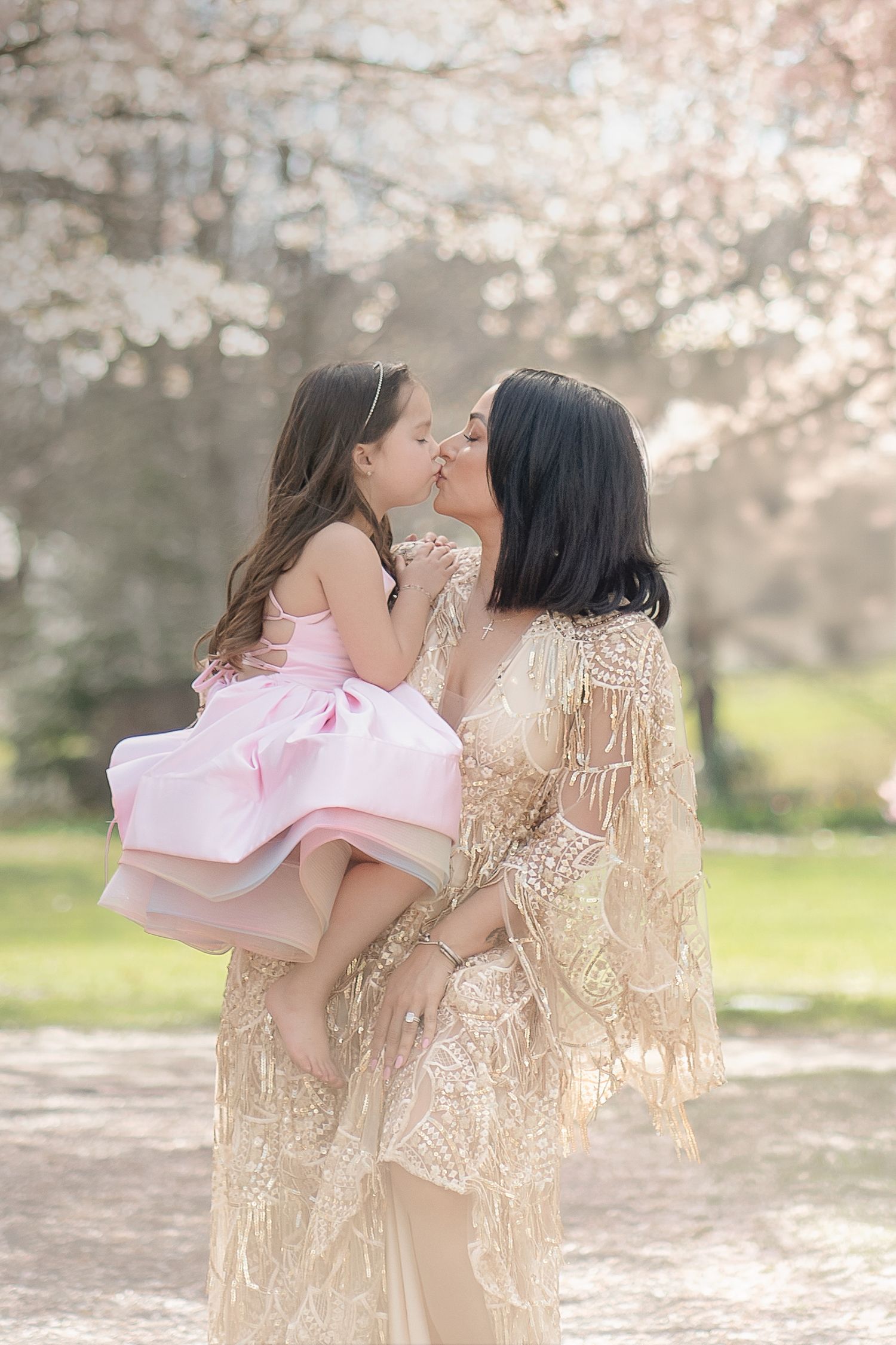 A tender moment captured in a series of photos under blooming cherry blossoms with soft pink petals falling.