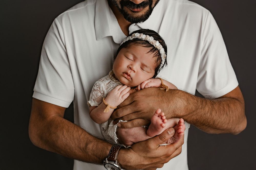 A series of black and white photographs showing a baby being gently cradled in someone's arms.