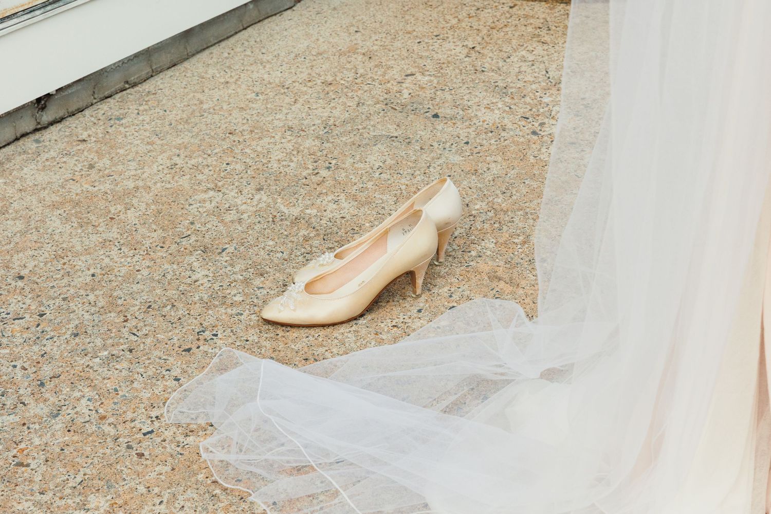 Detail shots of a flowing white wedding dress veil against a textured ground.