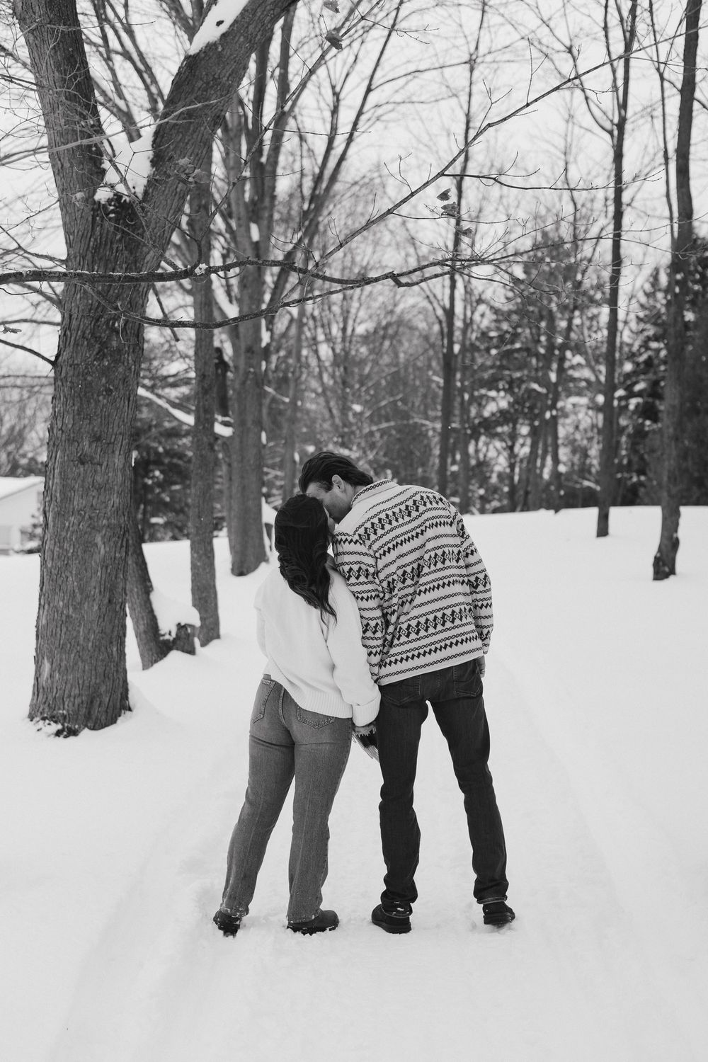 A black and white winter scene shows people playing in the snow among bare trees.