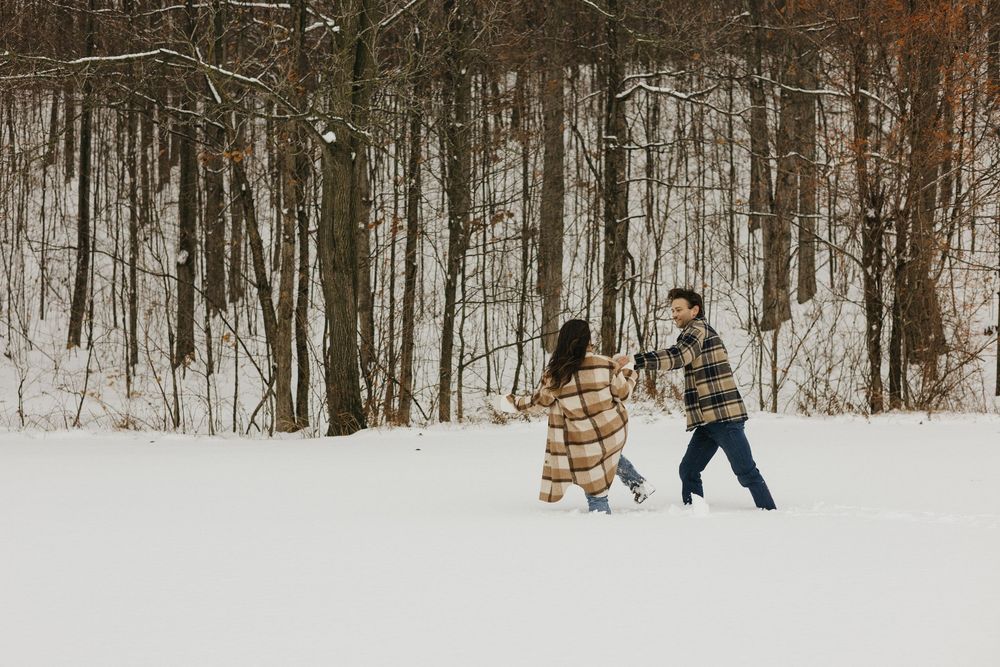 A group of people enjoying a winter walk through a snowy forest trail on a bright day.